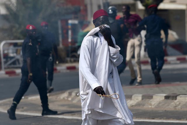 A man covers his face against tear gas fired by police during a protest in Dakar, Senegal
